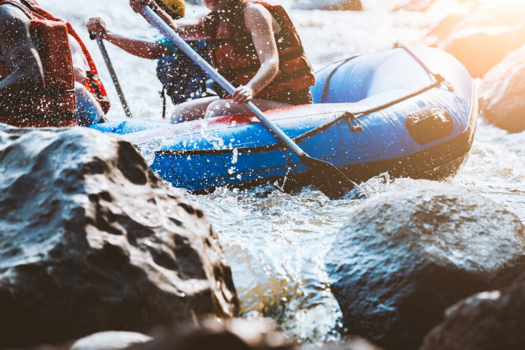 Dettaglio ravvicinato di giovani in gommone durante un'escursione di rafting, tra schizzi d'acqua e rocce del fiume - attualita.it Dettaglio ravvicinato di giovani in gommone durante un'escursione di rafting, tra schizzi d'acqua e rocce del fiume