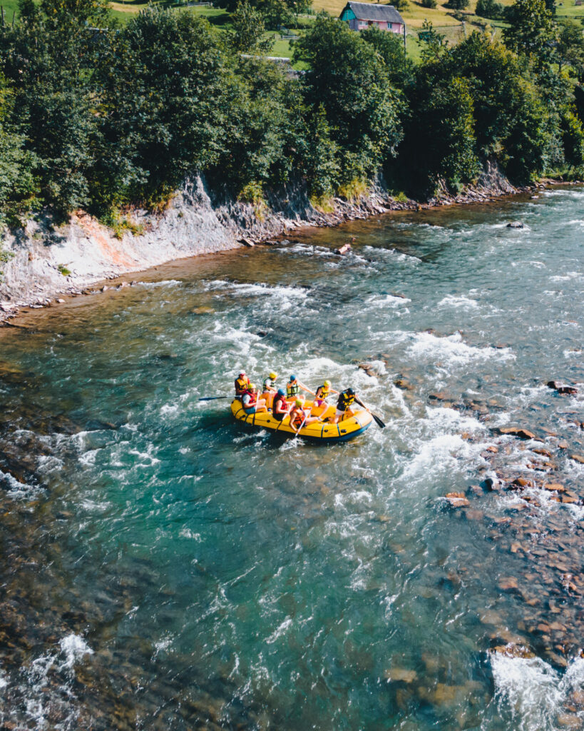 Gommone giallo con gruppo di persone fa rafting su un fiume alpino dalle acque limpide in estate, circondato da paesaggio montano - attualita.it Gommone giallo con gruppo di persone fa rafting su un fiume alpino dalle acque limpide in estate, circondato da paesaggio montano