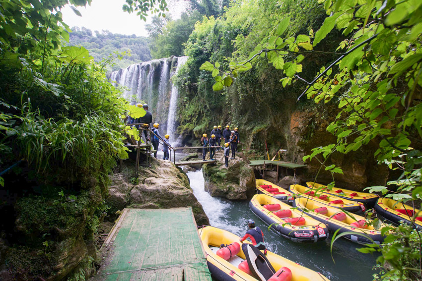 Imbarco rafting alle Cascate delle Marmore con gommoni gialli e gruppo di partecipanti sotto la cascata
